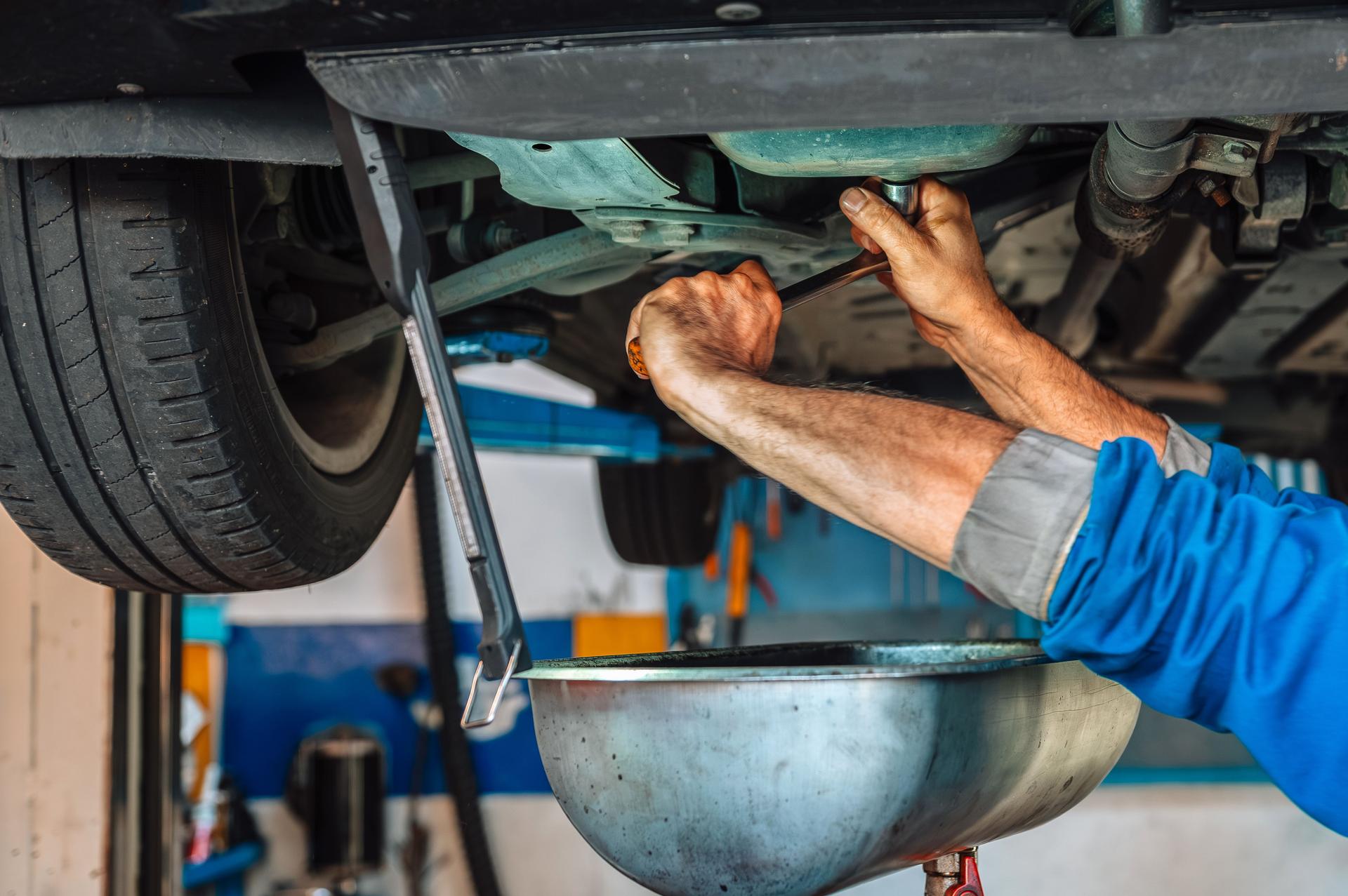 Mechanic changing car engine oil during service
