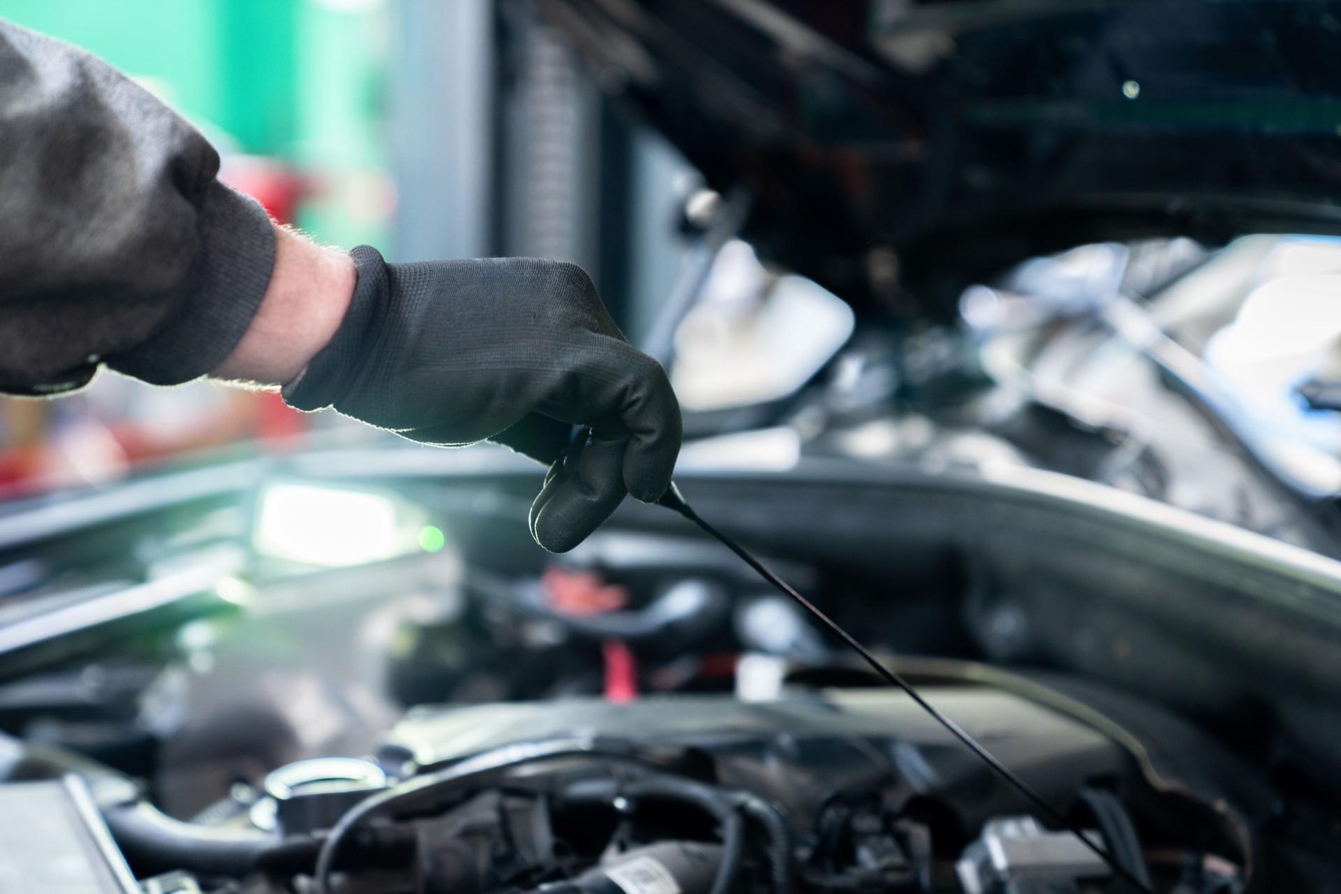 Serviceman checks the oil level in a car engine