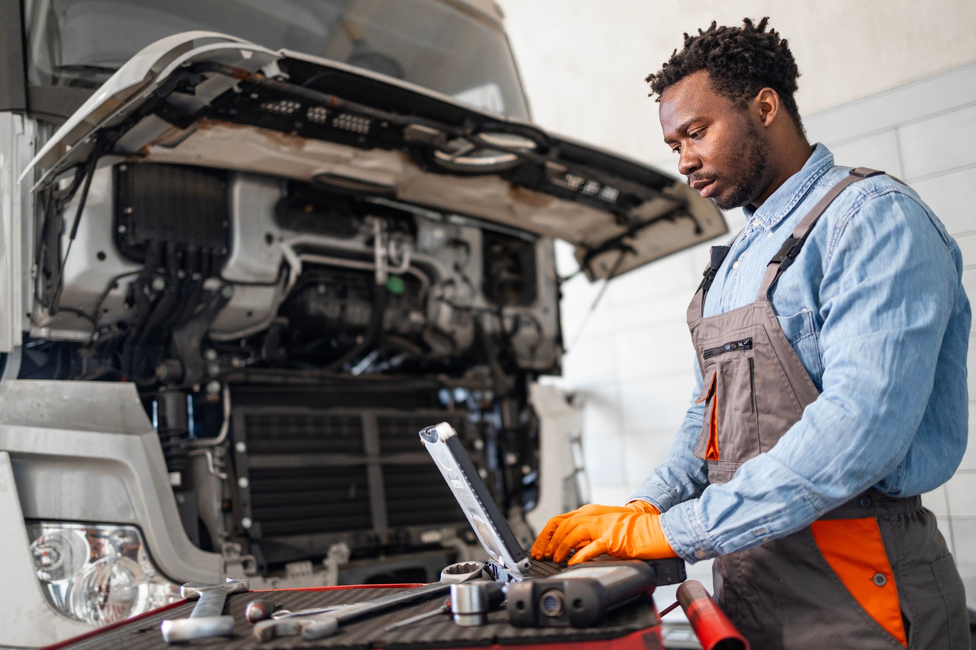 Confident black mechanic repairing the truck in workshop.
