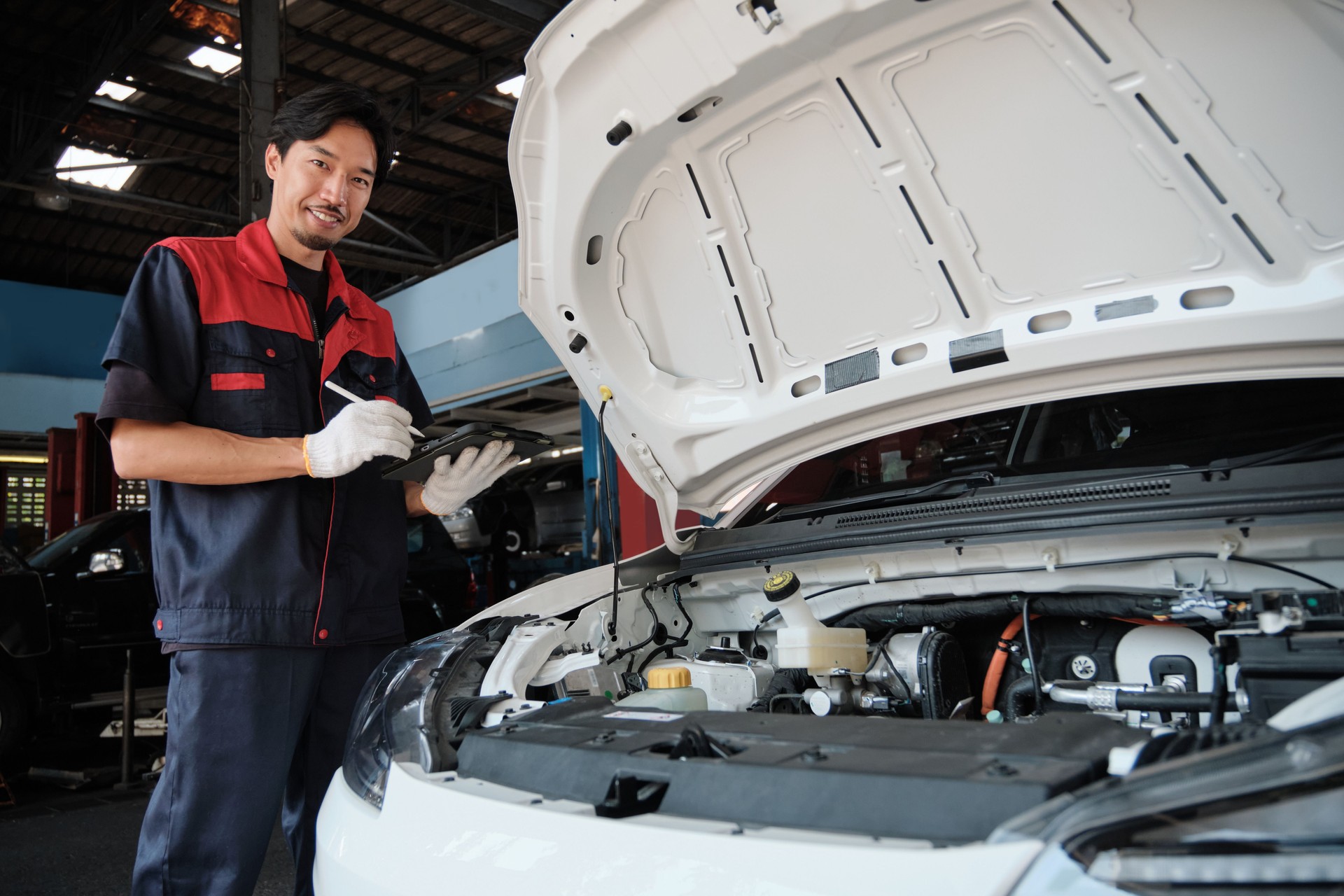 Asian male mechanic worker inspects an EV car in the garage station.