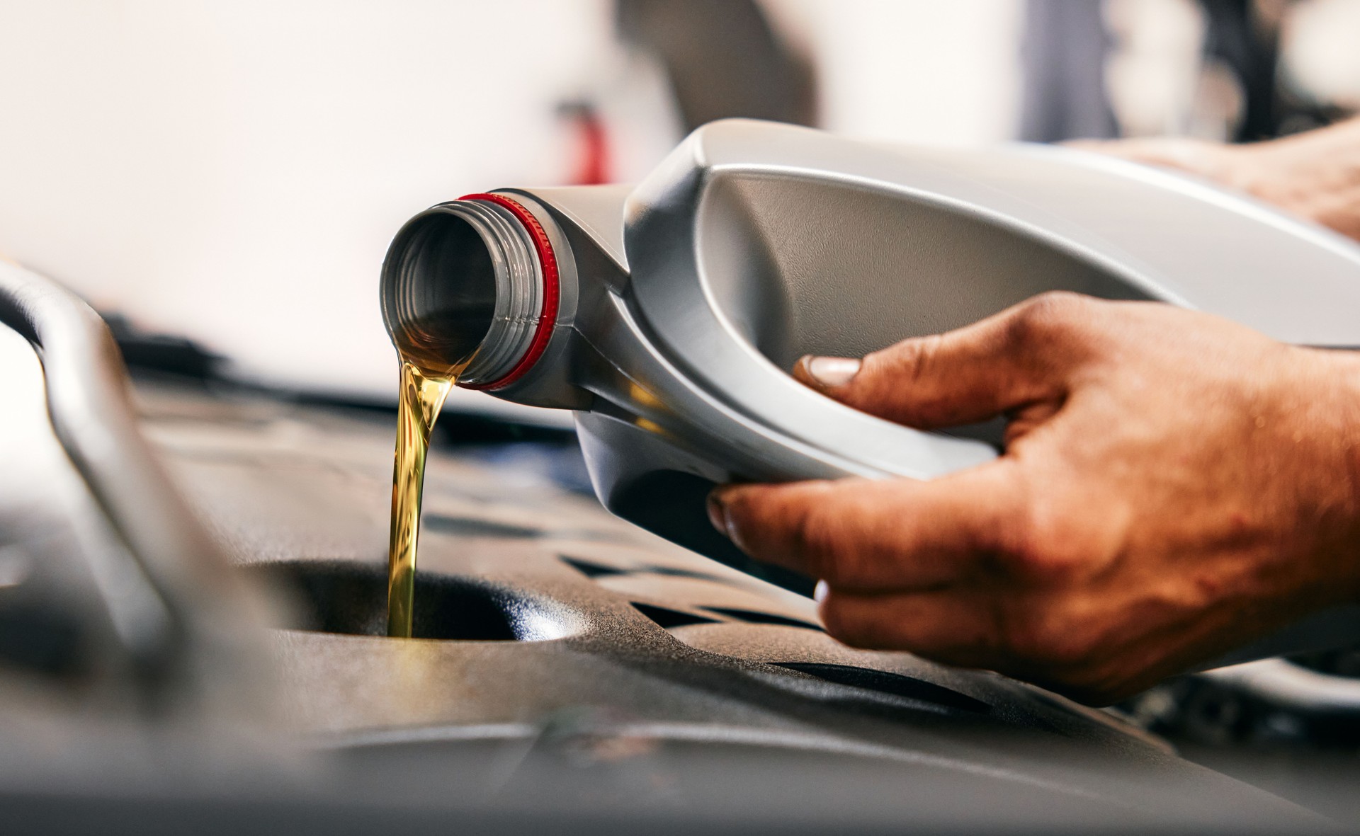 Close-up of car mechanic pouring new oil to car engine