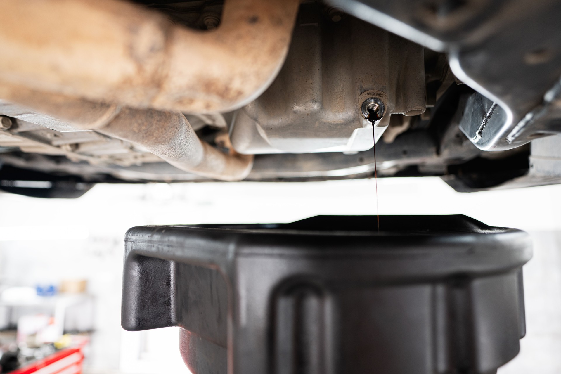 Car engine oil change process with oil draining pan below
