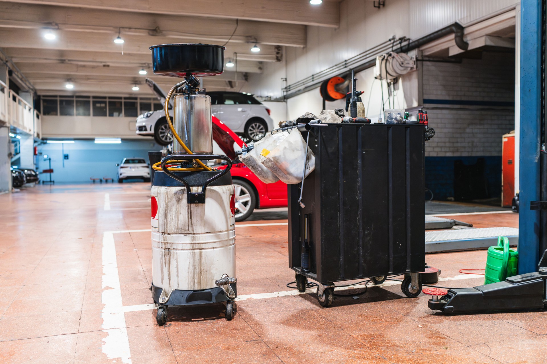 Oil collection tank and tools cart in a car repair shop